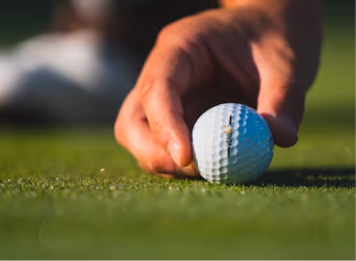 Hand placing golf ball on green, close-up of dimpled white ball
